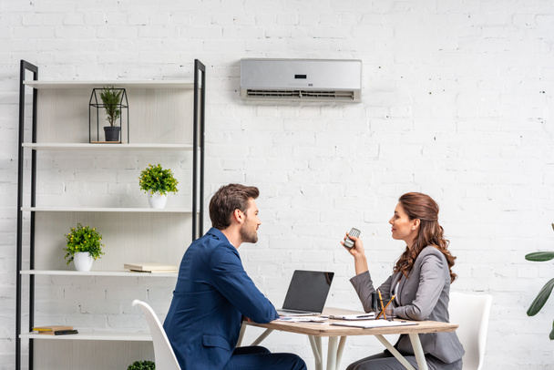 socios de negocios hablando mientras están sentados en el lugar de trabajo bajo el aire acondicionado
  - Foto, imagen