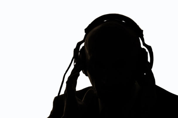 Tajný agent v obrysovém světle přeslechne konverzaci a poslouchá zvuk ve sluchátkách. - Fotografie, Obrázek