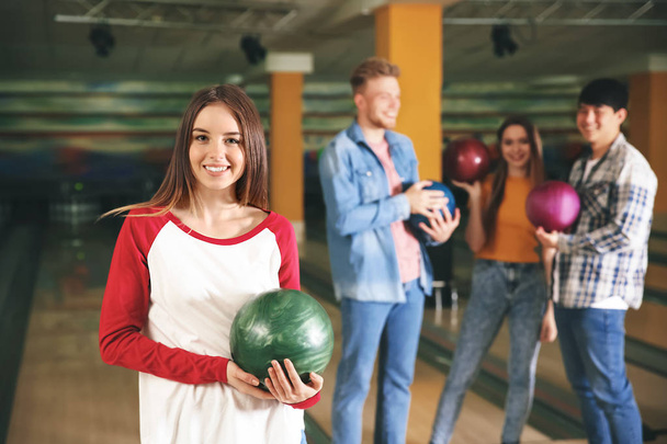 Fiatal nő barátaival bowling klubban - Fotó, kép