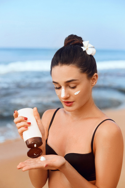 Suntan Lotion. Sexy Young Woman Applying Sunscreen Solar Cream on the beach.Sun Protection. Sun Cream. Skin and Body Care.Girl Holding Moisturizing Sunblock. Skin Protection - Fotó, kép