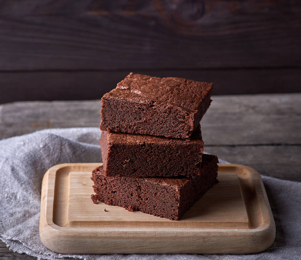 Stapel von gebackenen quadratischen Stücken Schokoladen-Brownie-Kuchen  - Foto, Bild
