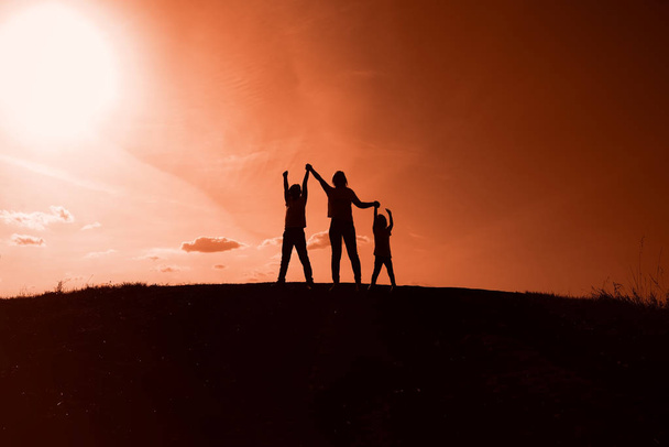 silhouettes of mom, son and daughter on sunset background - Foto, Bild