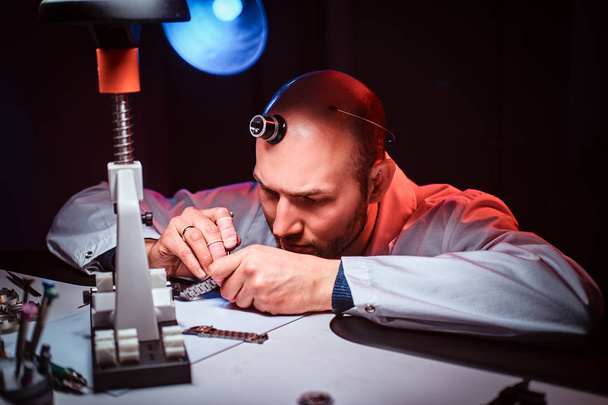 Mature watchmaker is working at his own studio. - Foto, Bild