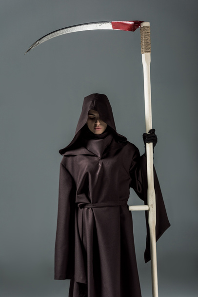 woman in death costume holding scythe on grey - Foto, afbeelding
