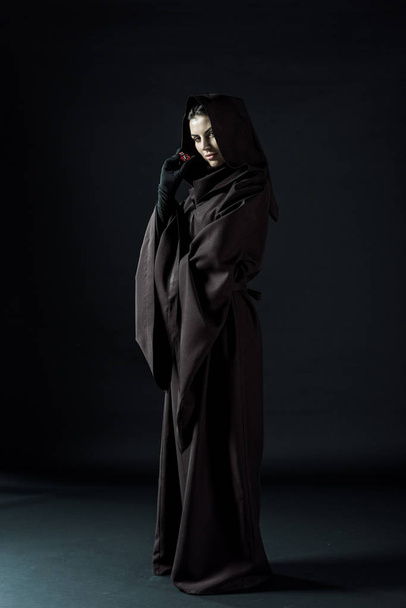 full length view of woman in death costume holding dice on black - Photo, Image