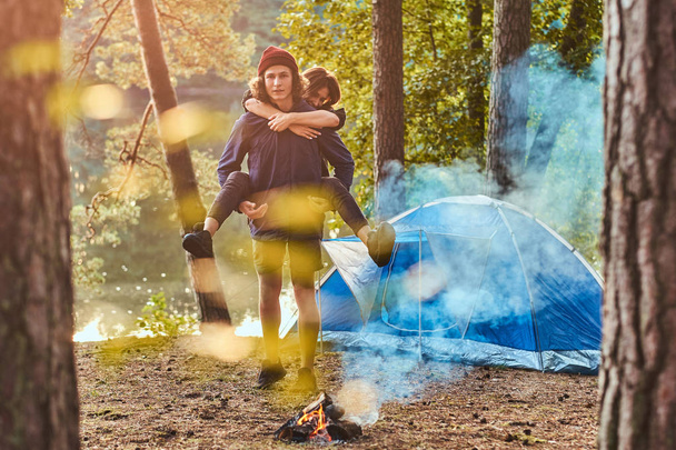 Young romantic couple have fun in summer forest near their tent - Foto, afbeelding