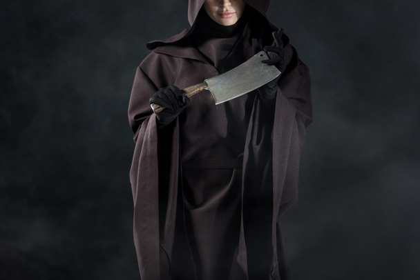vista parziale della donna in costume da morte tenuta mannaia su nero
 - Foto, immagini