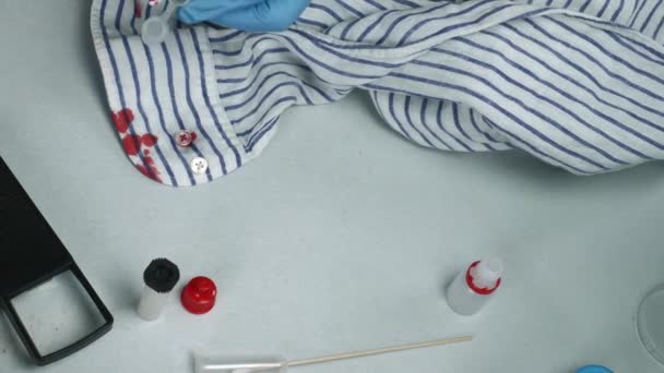 Politie deskundige onderzoekt bloed in een knop van een shirt het toneel van een misdrijf - Video