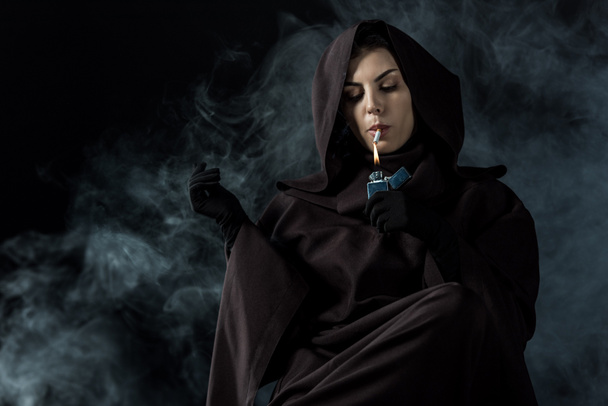 γυναίκα με στολή θανάτου ανάβει τσιγάρο στο μαύρο - Φωτογραφία, εικόνα