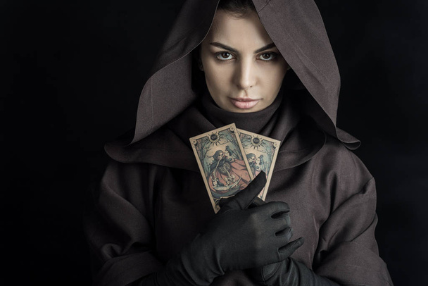 KYIV, UKRAINE - APRIL 18, 2019: attractive woman in death costume holding tarot cards on black - Foto, Bild