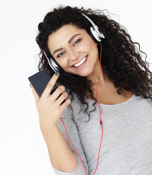 lifestyle and people concept: Beautiful young woman listening to music in headphones with smartphone - Foto, immagini