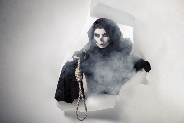 Nainen kuoleman puku tilalla roikkuu hirttosilmukka ja päästä ulos reikä paperissa
 - Valokuva, kuva