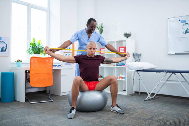 Therapist helping his patient stretching arms after injury - Foto, imagen