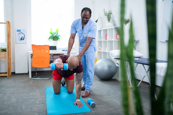 Therapist assisting patient with back injury doing exercises - Fotoğraf, Görsel