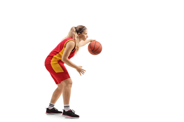 Full length profile shot of a female basketball player leading a ball isolated on white background - Foto, afbeelding