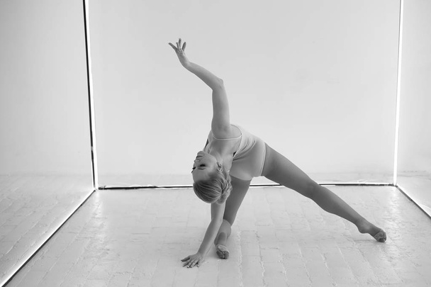 Graceful gymnast in body tights on a white background makes complex shapes.Sports, gymnastics, stretching. - Фото, зображення