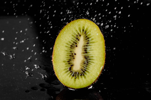 Kiwi with splashing water on black background. Citrus fruit with water drops. Healthy freshness food. Green fruit with vitamin - Foto, Imagen