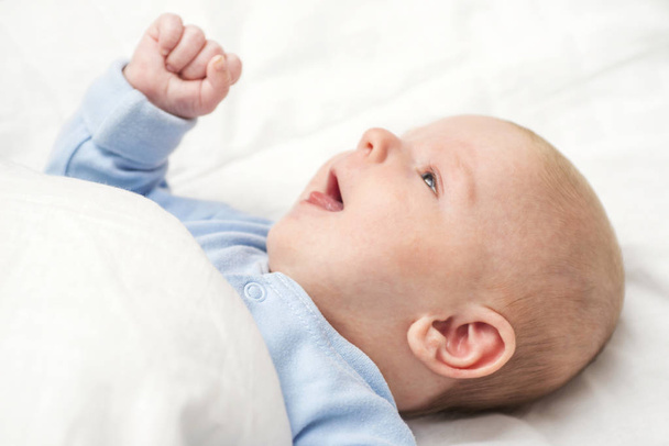 Новорожденный лежит в постели. Счастливый ребенок, лежащий на одеяле - Фото, изображение