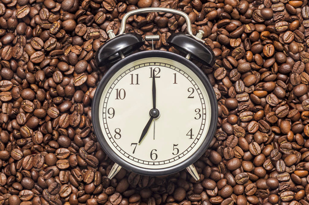 Fekete óra és kávébab a háttérben. Ébresztőóra a kávébab. Kávékészítési idő fogalma - Fotó, kép