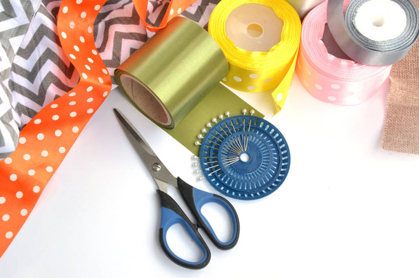 flache Lage mit farbigen Bändern, Scheren und Nadeln auf weißem Hintergrund - Foto, Bild