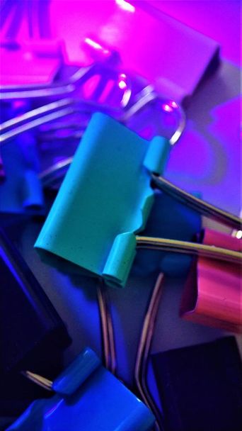 Farbige Büroklammern unter ultravioletten Makro-Nahaufnahmen für den Hintergrund - Foto, Bild
