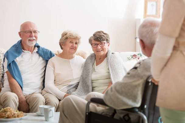 Group of senior friends sitting together in common living room of nursing home - Foto, imagen
