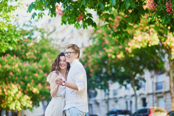 Happy romantic couple in Paris, hugging under pink chestnuts in full bloom - Photo, image