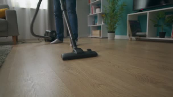 Close-up shot of Man cleaning cozy apartment with vacuum cleaner - Felvétel, videó