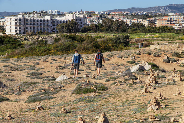 Dois amigos entra no próximo túmulo histórico em grande escavação em Paphos, é nomeado Túmulos dos Reis e é destino muito famoso em Chipre. Dois homens caminham lado a lado no parque
 - Foto, Imagem