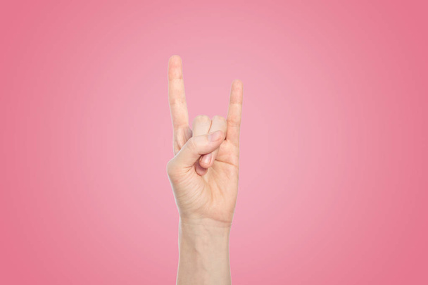 Hand show rock gesture on a pink background, close up. - Photo, Image