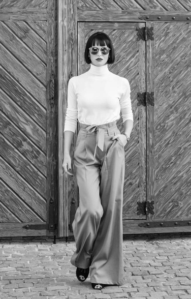 Fashionable outfit slim tall lady. Fashion and style concept. Woman walk in loose pants. Woman fashionable brunette stand outdoors wooden background. Girl with makeup posing in fashionable clothes - Fotografie, Obrázek