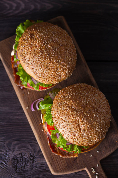 Ahşap doğrama tahtası üzerinde pastırma ile iki lezzetli ev yapımı sığır burger. Yukarıdan görüntüle, en iyi stüdyo çekimi - Fotoğraf, Görsel
