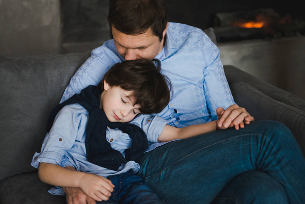 Father with little son sitting on the sofa. Father's day. Happy young father embracing kid sitting on sofa, loving caring dad hugging little boy. Father with little boy using digital tablet at home - Photo, Image