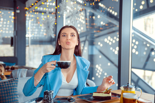 жінка погладжує губи, дивлячись, що тримає чашку кави
 - Фото, зображення