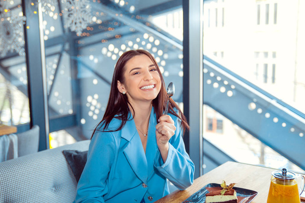 woman eating dessert in cafe holding spoon smiling - Fotó, kép