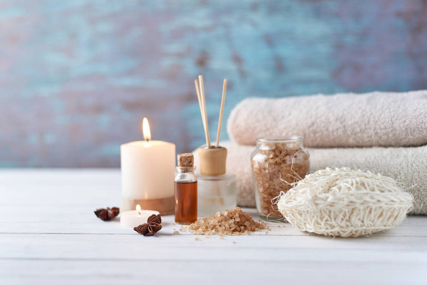 Toallas, velas y aceite de masaje sobre mesa blanca
 - Foto, Imagen