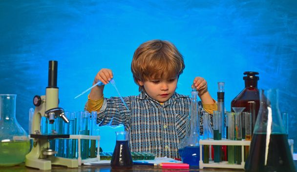 Back to school and happy time Kid is learning in class on background of blackboard. Education. Lab microscope and testing tubes. Chemistry lesson - Foto, Bild