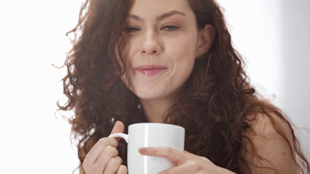 beautiful girl drinking coffee, looking at camera and smiling in morning - Materiał filmowy, wideo