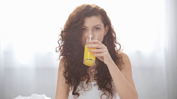 hermosa chica bebiendo jugo de naranja, mirando a la cámara y sonriendo en casa
 - Metraje, vídeo
