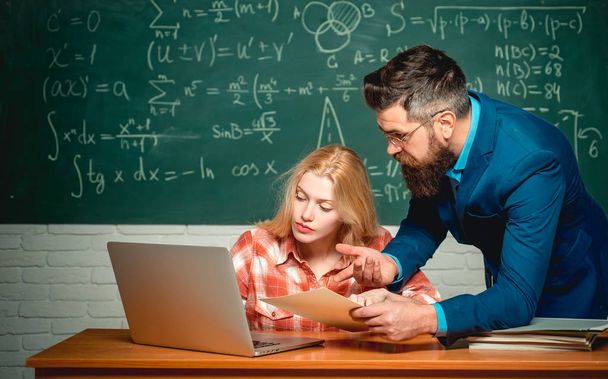 Teacher collaborates with colleagues. Back to school and Education concept. Young teacher near chalkboard in school classroom. Blackboard for copy space text. - 写真・画像