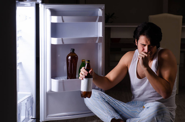 Άντρας σπάσιμο διατροφή τη νύχτα κοντά στο ψυγείο - Φωτογραφία, εικόνα