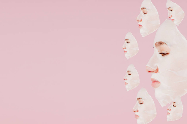 Beautiful young woman is applying a cosmetic tissue mask on a face on a pink background. Healthcare and beauty treatment and technology concept - Φωτογραφία, εικόνα