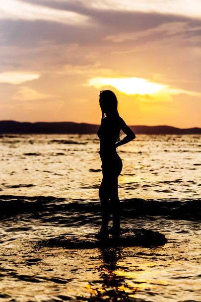 Sexy woman body on silhouette in the sea at sunset  - Fotografie, Obrázek