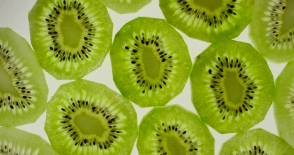 Kiwi-Fruchtscheiben rotieren auf einem strahlend weißen Hintergrund. Nahaufnahme von oben, aufgenommen mit roter 6k-Kamera - Filmmaterial, Video