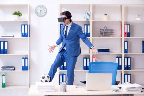 Молодий красивий бізнесмен грає у футбол з віртуальними окулярами
  - Фото, зображення