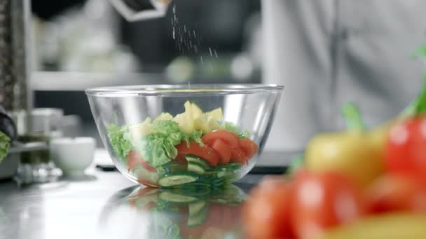 Chef man salting salad at kitchen restaurant. Closeup hand salting vegetables. - Filmagem, Vídeo