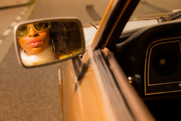 ρετρό 70s Αφρο μόδας γυναίκα με γυαλιά ηλίου που ψάχνετε στον καθρέφτη o - Φωτογραφία, εικόνα