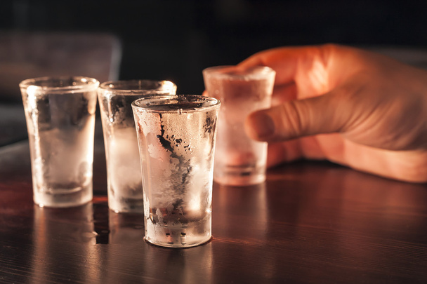 Shot glasses of vodka in hand. - Photo, Image