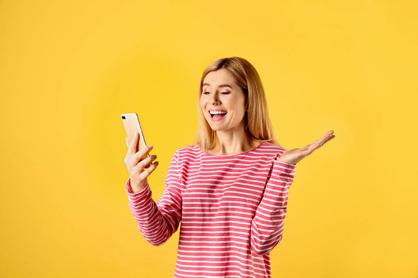 Woman using mobile phone for video chat on color background - Fotoğraf, Görsel