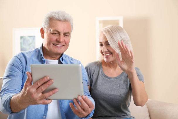Mature couple using video chat on tablet at home - Foto, immagini